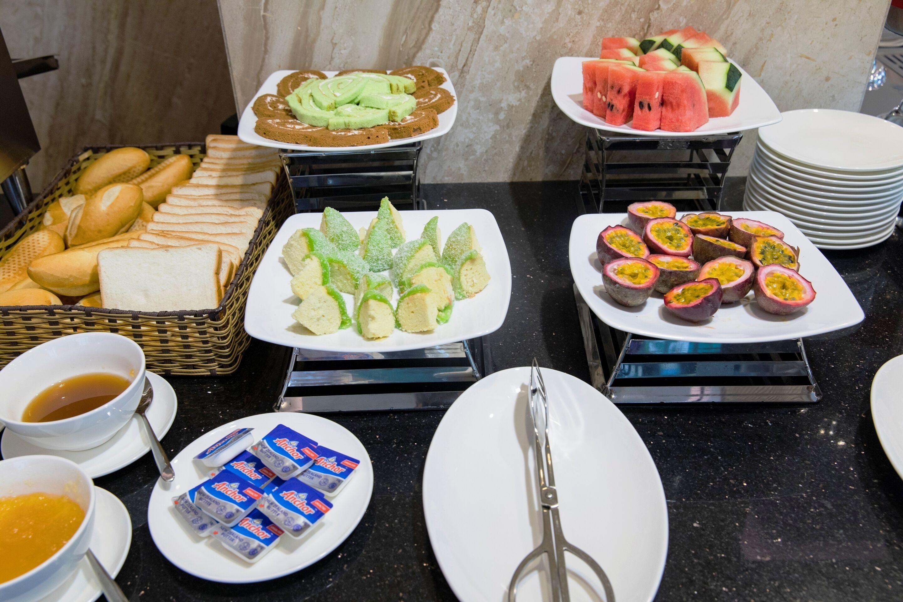Un buffet proposant une variété d’aliments, notamment du pain, des légumes coupés en tranches et des fruits tropicaux.