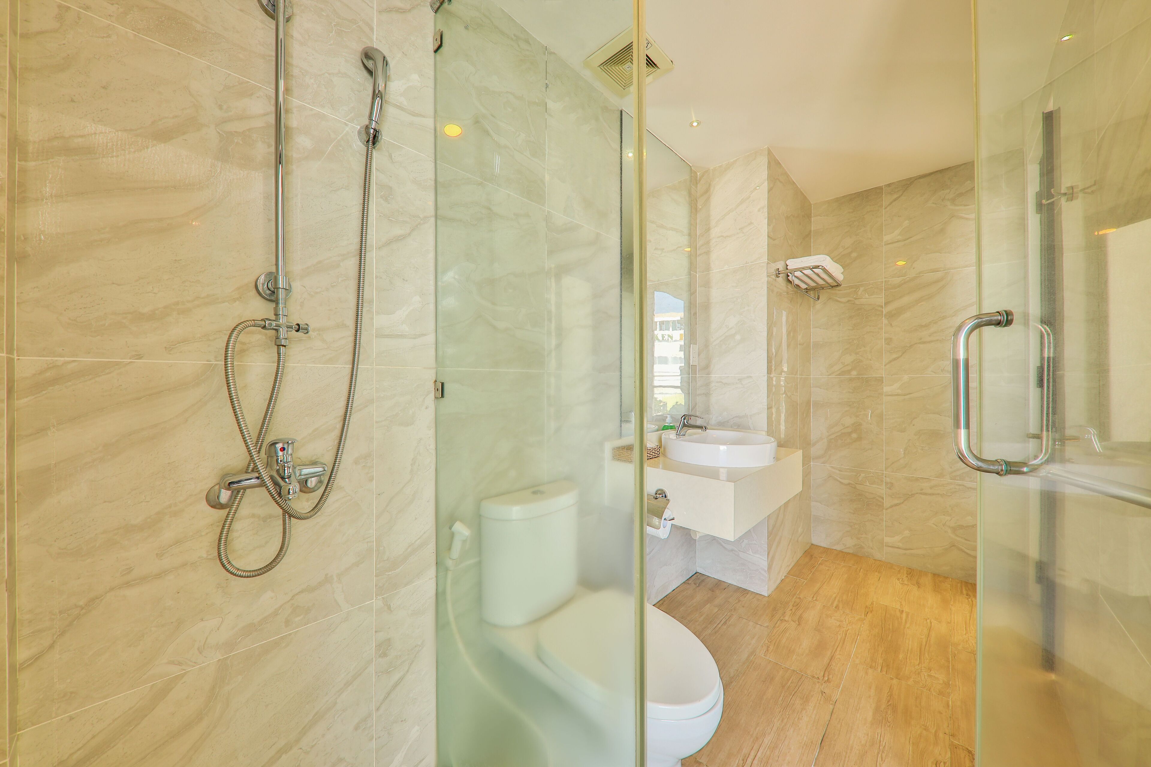 A modern bathroom with a glass partition, a shower, a toilet, and a sink.