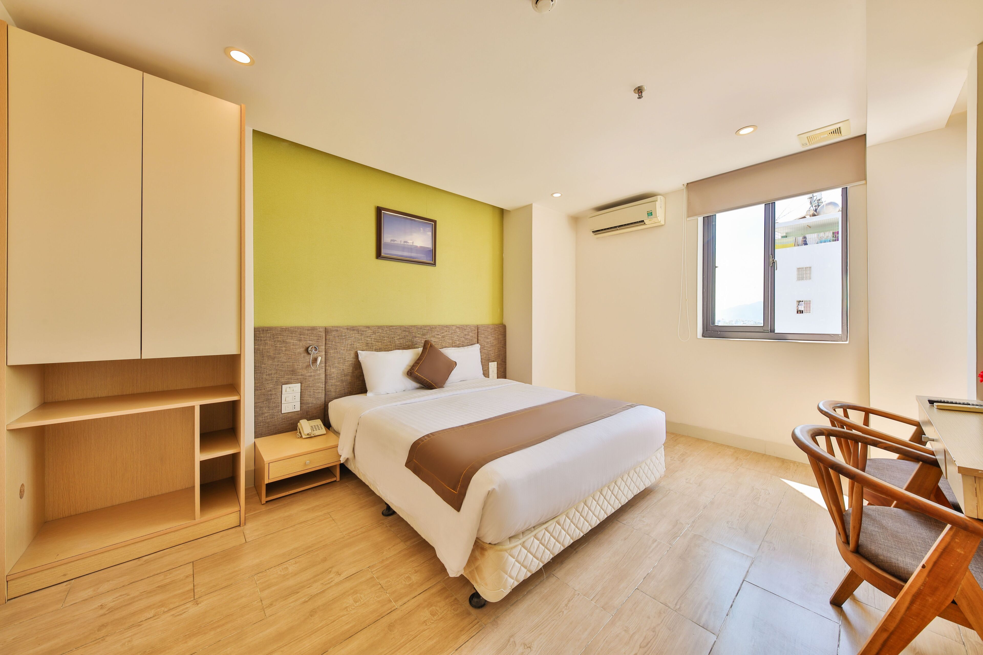 A hotel room with a bed, wooden furniture, a desk, and a window.