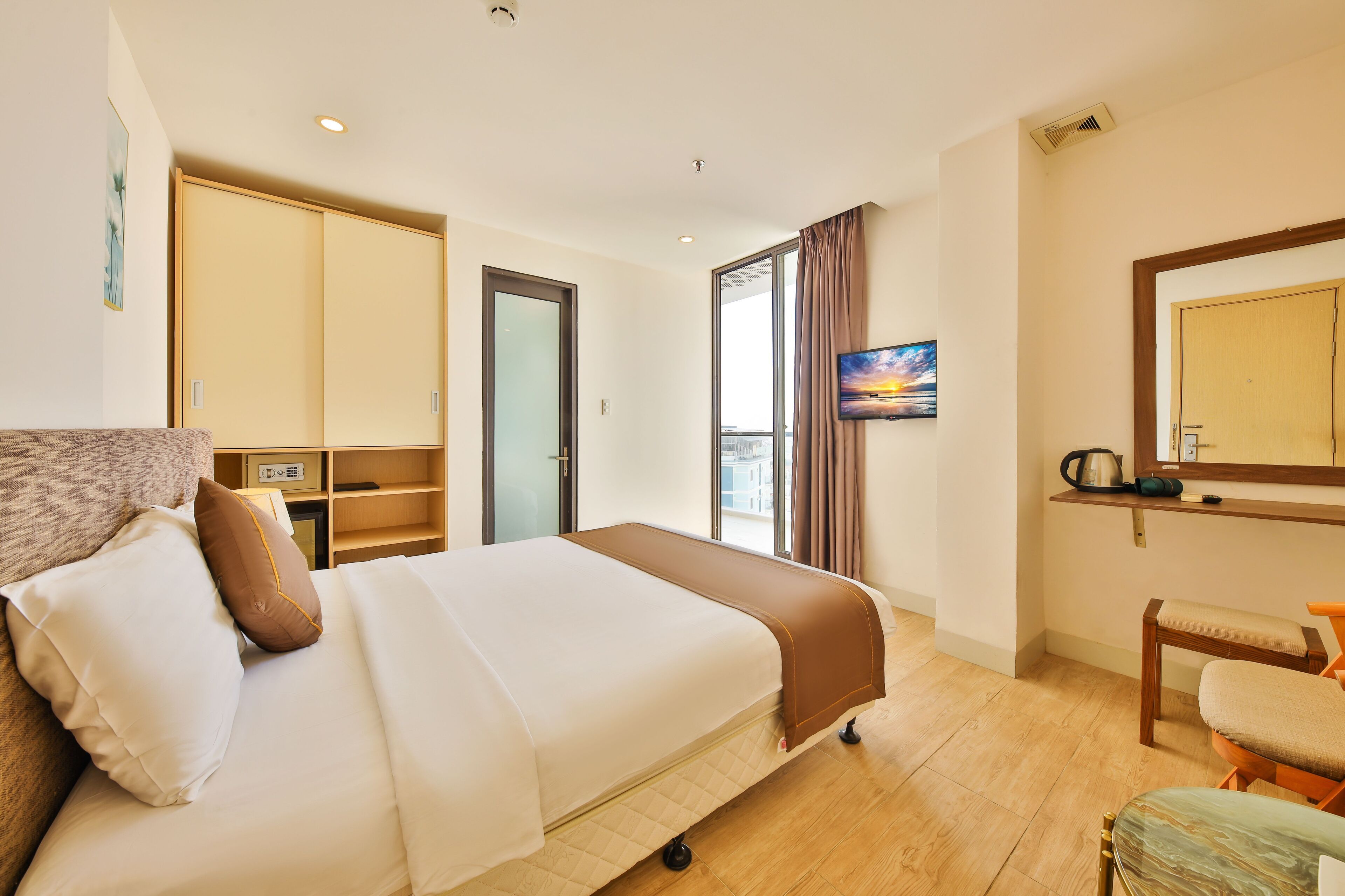 Una habitación de hotel con cama, escritorio, silla, televisión y ventana con cortinas.