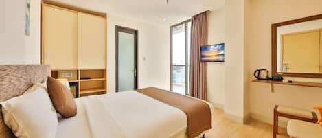 Una habitación de hotel con cama, escritorio, silla, televisión y ventana con cortinas.