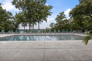 A swimming pool with lounge chairs and trees in the background.