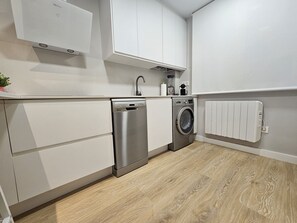 A compact kitchen with a dishwasher, washing machine, and a white radiator. - 1A126 ALQ TEMPORADA  centrico en Gijon (Gijón)