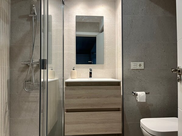 A modern bathroom with a glass shower enclosure, a wooden vanity with a mirror, and a toilet. - 1A126 ALQ TEMPORADA  centrico en Gijon (Gijón)