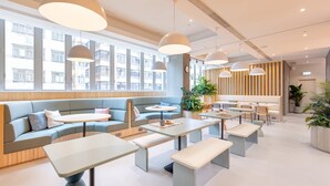 Un intérieur moderne avec des coins salon, des tables et de grandes fenêtres offrant une vue sur la ville.