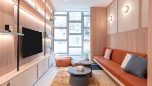 Un salon moderne doté d’un téléviseur à écran plat, de lambris en bois, d’un canapé avec des coussins et d’une table basse.