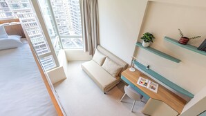 Une chambre d’hôtel moderne équipée d’un lit, d’un canapé, d’un bureau et offrant une vue sur le paysage urbain.