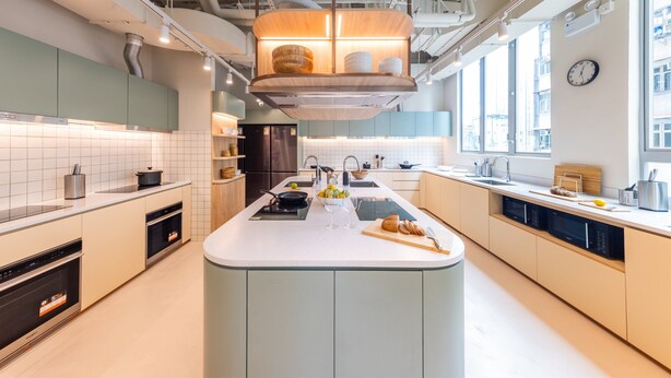 Une cuisine moderne dotée d’un îlot central, d’appareils électroménagers intégrés et bénéficiant d’un éclairage naturel abondant.