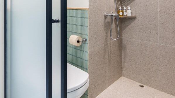 Un baño con inodoro, ducha y estante de productos de higiene personal.