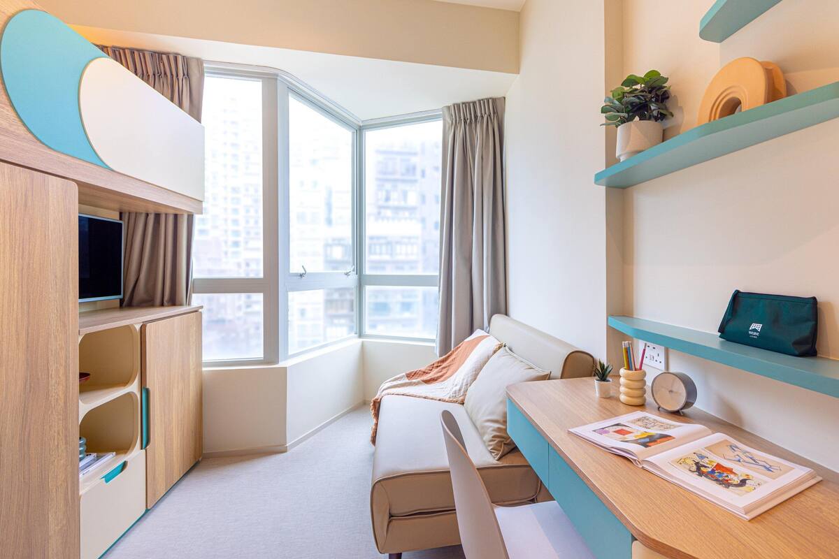 Una habitación moderna con sofá, escritorio y estantería.