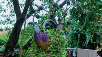 Una jaula con un pájaro y follaje verde.