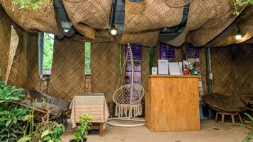 Een rustiek interieur met geweven wanden, een houten bureau en hangstoelen.
