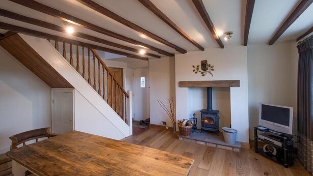 Ein Holzesstisch in einem Raum mit Kamin, Fernseher und Treppe.