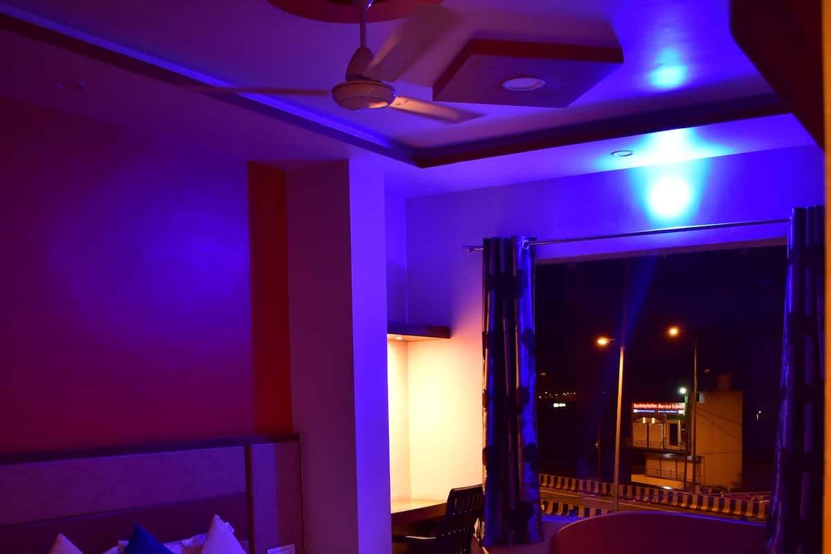 A hotel room with a large bed, a ceiling fan, and a view of the outside at night.