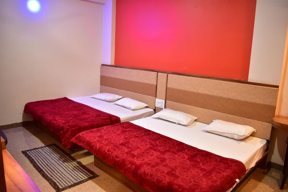 A hotel room with two beds, each with a red bedspread and white pillows.