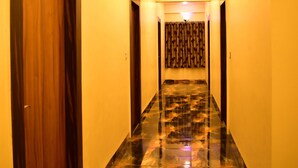 A hallway with a marble floor, wooden doors, and a ceiling light. - HOTEL JYOTI PALACE (Biaora)