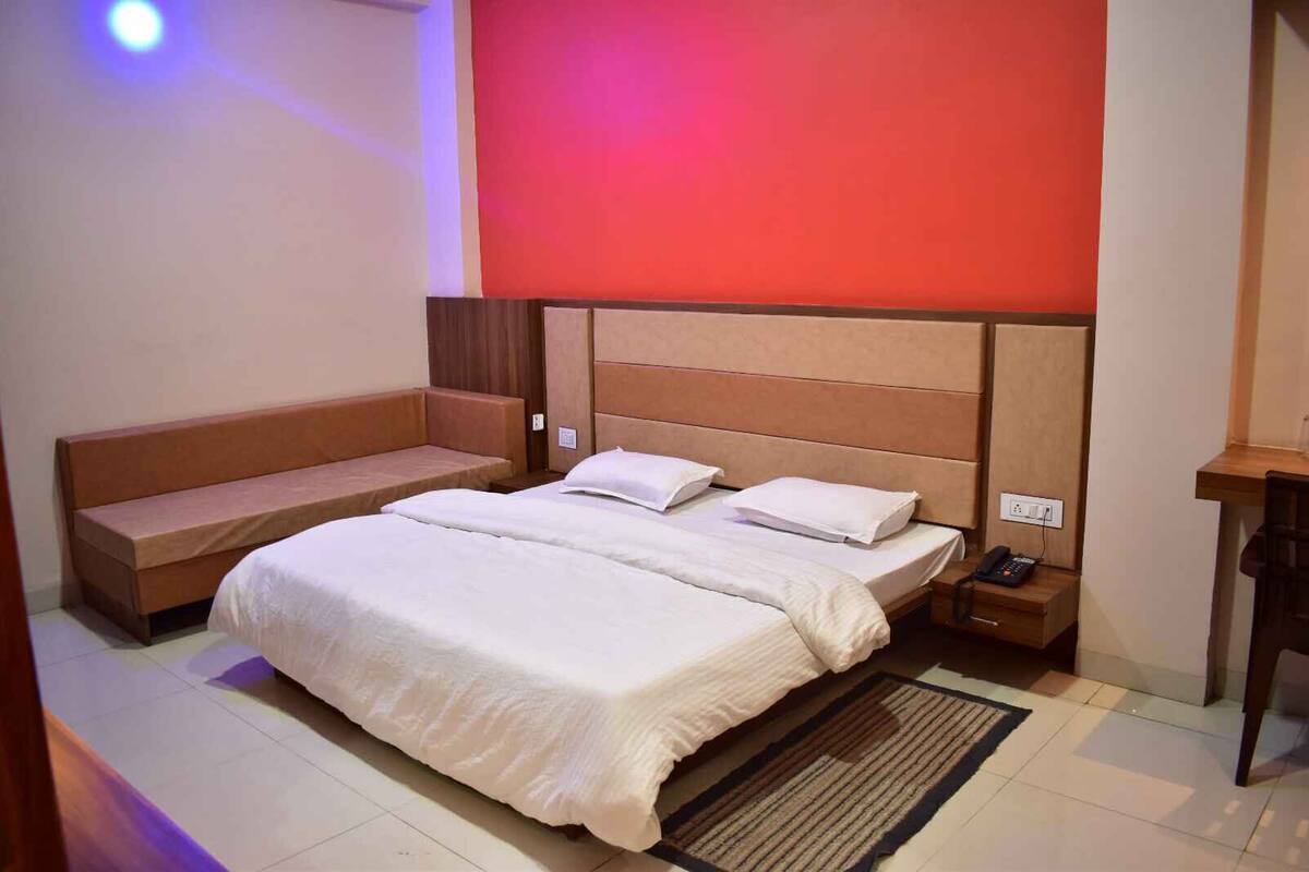 A hotel room with a large bed, a bench, a bedside table, and a nightstand.