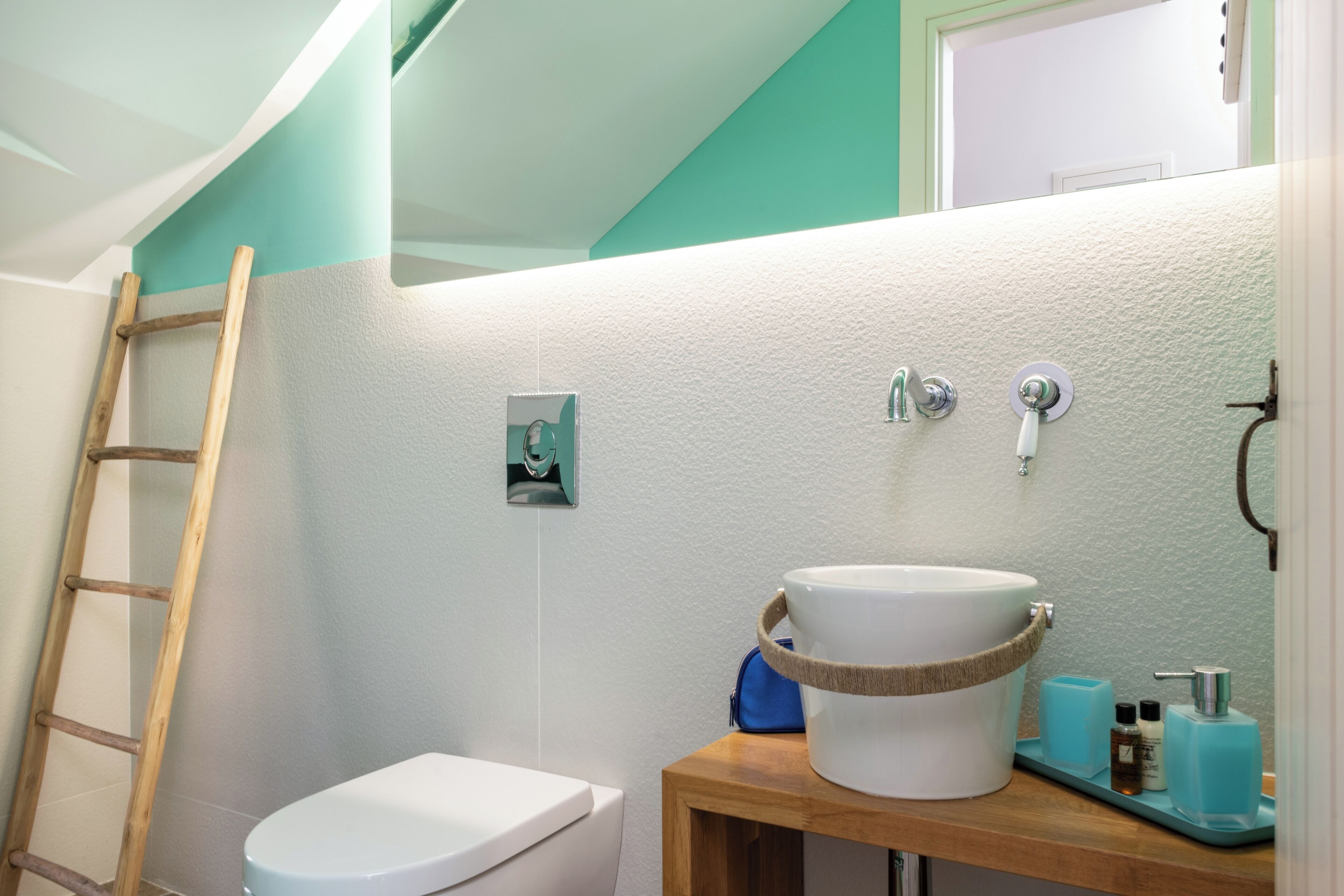 Une salle de bain avec des toilettes blanches, une étagère en bois contenant des articles de toilette et une échelle en bois.