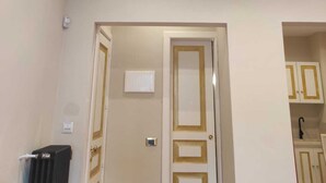 Habitación de hotel con puerta cerrada, un radiador y una vista parcial del baño, que incluye un lavamanos y armarios.