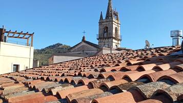 Terracotta roof tiles, a church with a bell tower, and a clear blue sky.