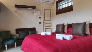 A hotel room with a large bed, a green armchair, a wooden headboard, and a window with a view.