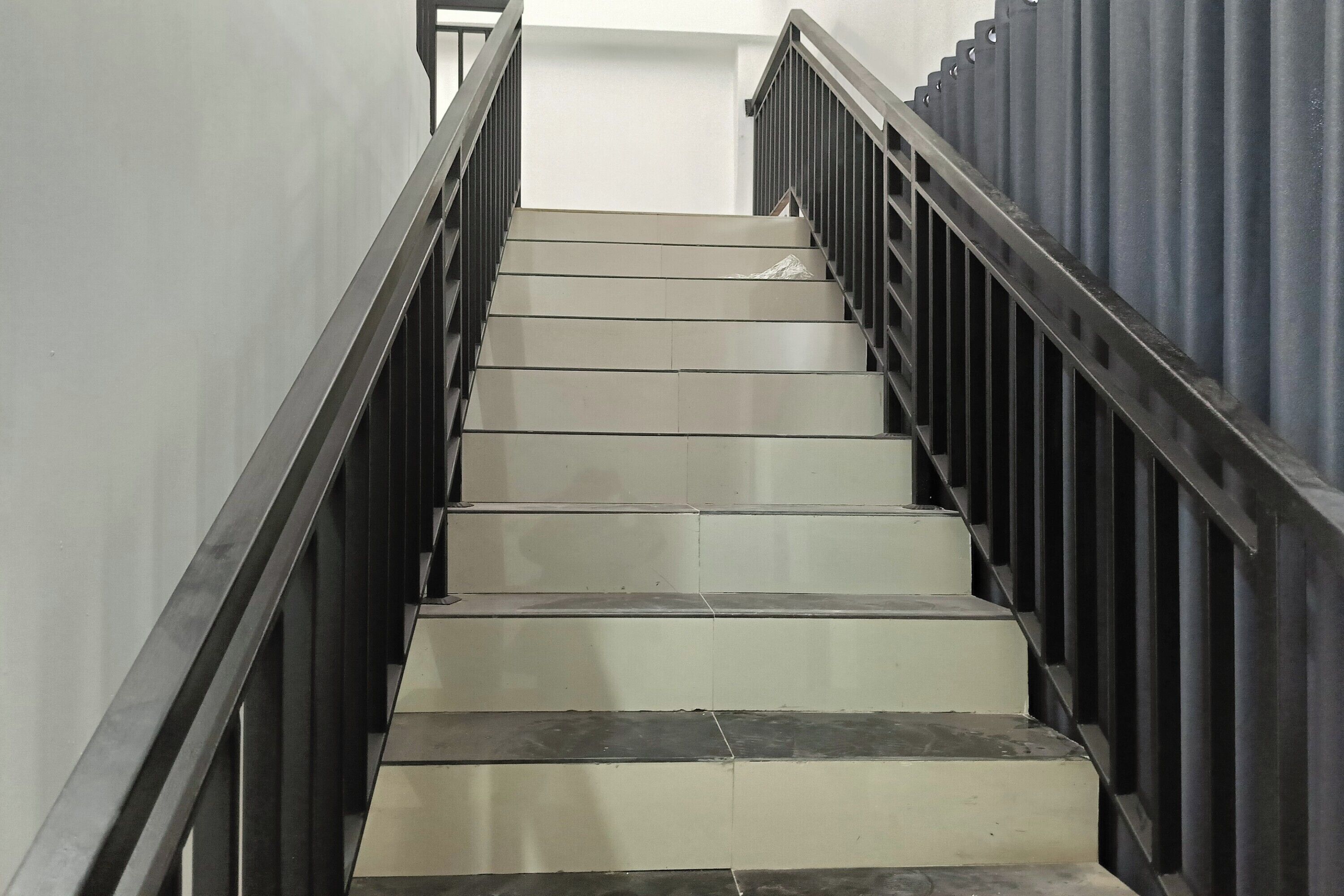 A staircase with a metal railing, leading upwards.
