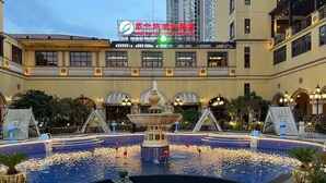 Un patio de hotel con una fuente central, zonas de estar y una piscina.