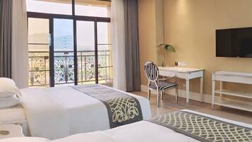 Habitación de hotel con dos camas, un escritorio, una silla, un televisor y un balcón con vistas.