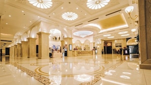 Un vestíbulo amplio con piso pulido, columnas decorativas y una recepción central.