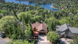 Une maison avec un garage, entourée d’une forêt dense et d’un lac.
