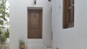 Un bâtiment étroit aux murs blancs, doté d’une porte en bois et de deux lanternes fixées au mur.