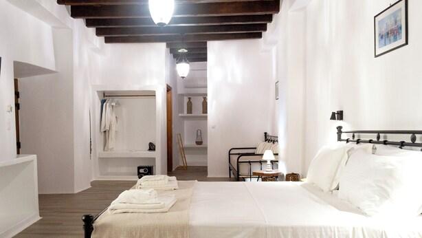 Une chambre à coucher comprenant un lit, une table de chevet, une lampe et une vue sur une salle de bain avec une douche et un porte-serviettes.