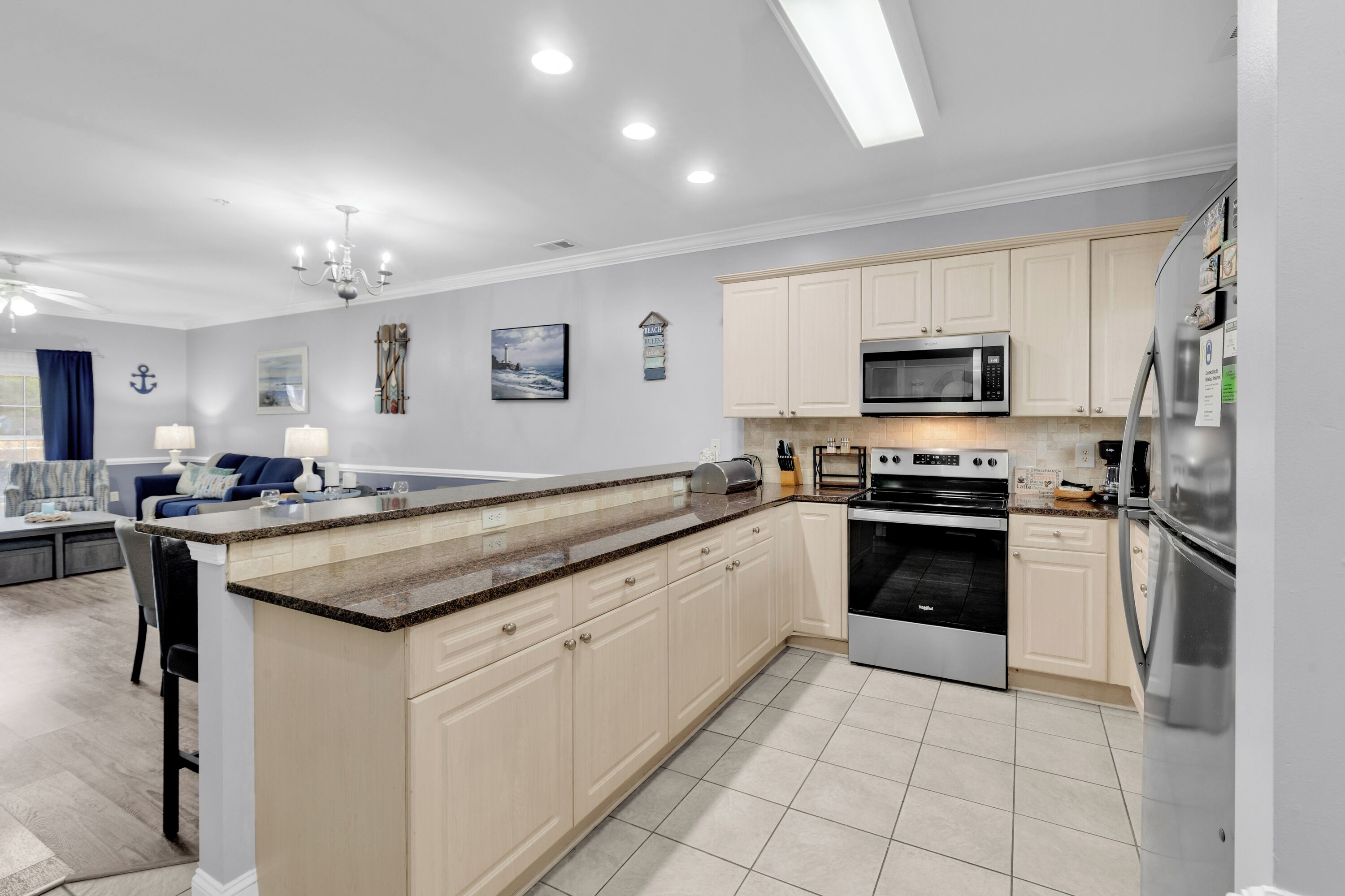 A modern kitchen with a central island, stainless steel appliances, and light-colored cabinetry.