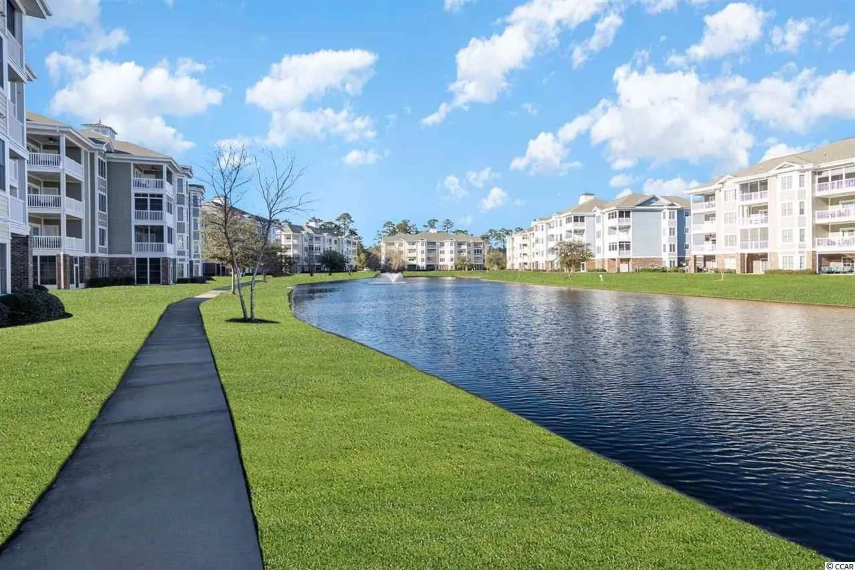 Zona residencial com um canal, um passeio pavimentado e edifícios altos com sacadas.