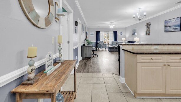A spacious kitchen with a central island, a dining area with a table and chairs, and a hallway leading to a living room. - Magnolia Pointe (Myrtle Beach)