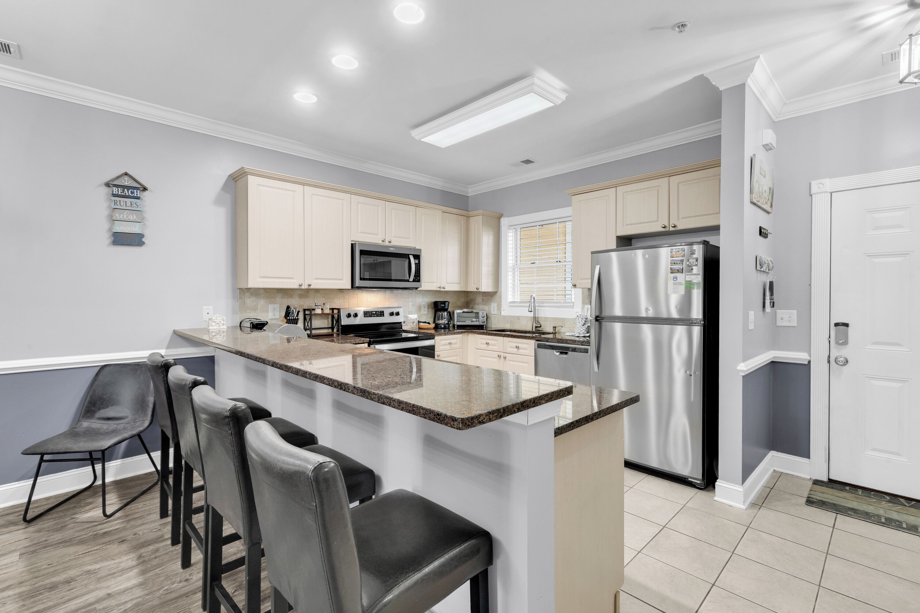 A modern kitchen with a central island, bar stools, and stainless steel appliances.