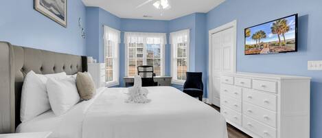 A bedroom with a bed, a dresser, a chair, and a television.