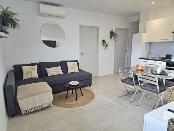 Cozy living space with a sofa, dining area, and kitchen, perfect for relaxing and enjoying meals.