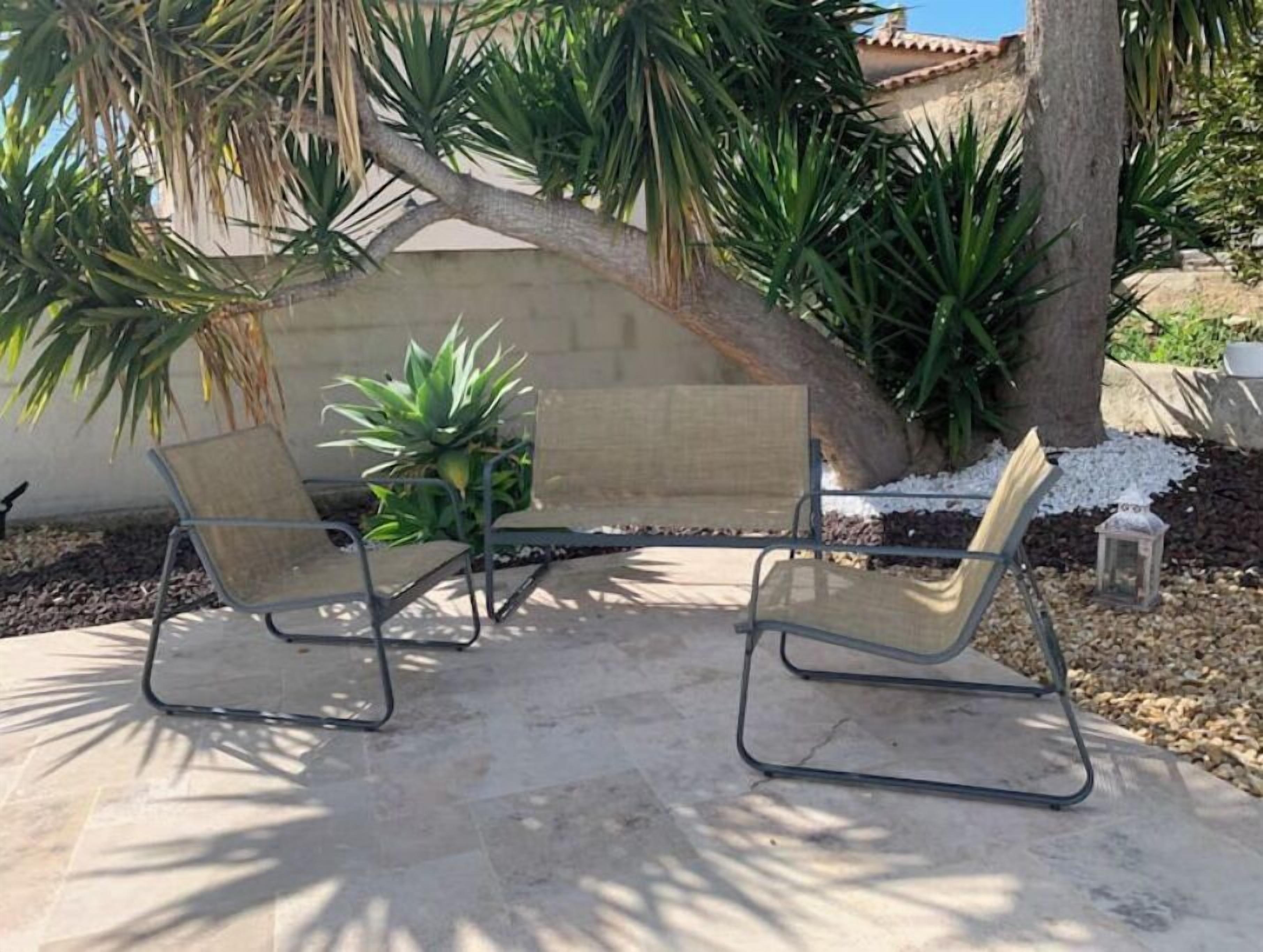An outdoor seating area with two metal-framed chairs and a small potted plant.