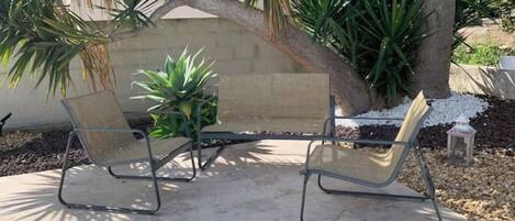 An outdoor seating area with two metal-framed chairs and a small potted plant.