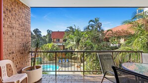 A balcony with a pool, chairs, and a table.