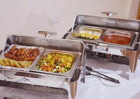 Un bufé con diversas opciones de comida, incluyendo salchichas, una ensalada y un plato con salsa roja.