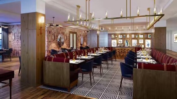 Een restaurant met een lange gedeelde tafel, zitjes en een vloer met patroon.