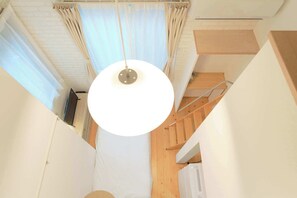 A narrow hallway with a white ceiling, a hanging light fixture, and a wooden staircase. - Nakano Five by Tranova (Tokyo)