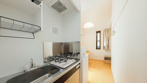 A compact kitchen with a sink, stove, and cabinets. - Nakano Five by Tranova (Tokyo)