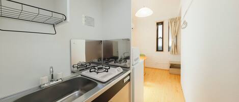 A compact kitchen with a sink, stove, and cabinets.