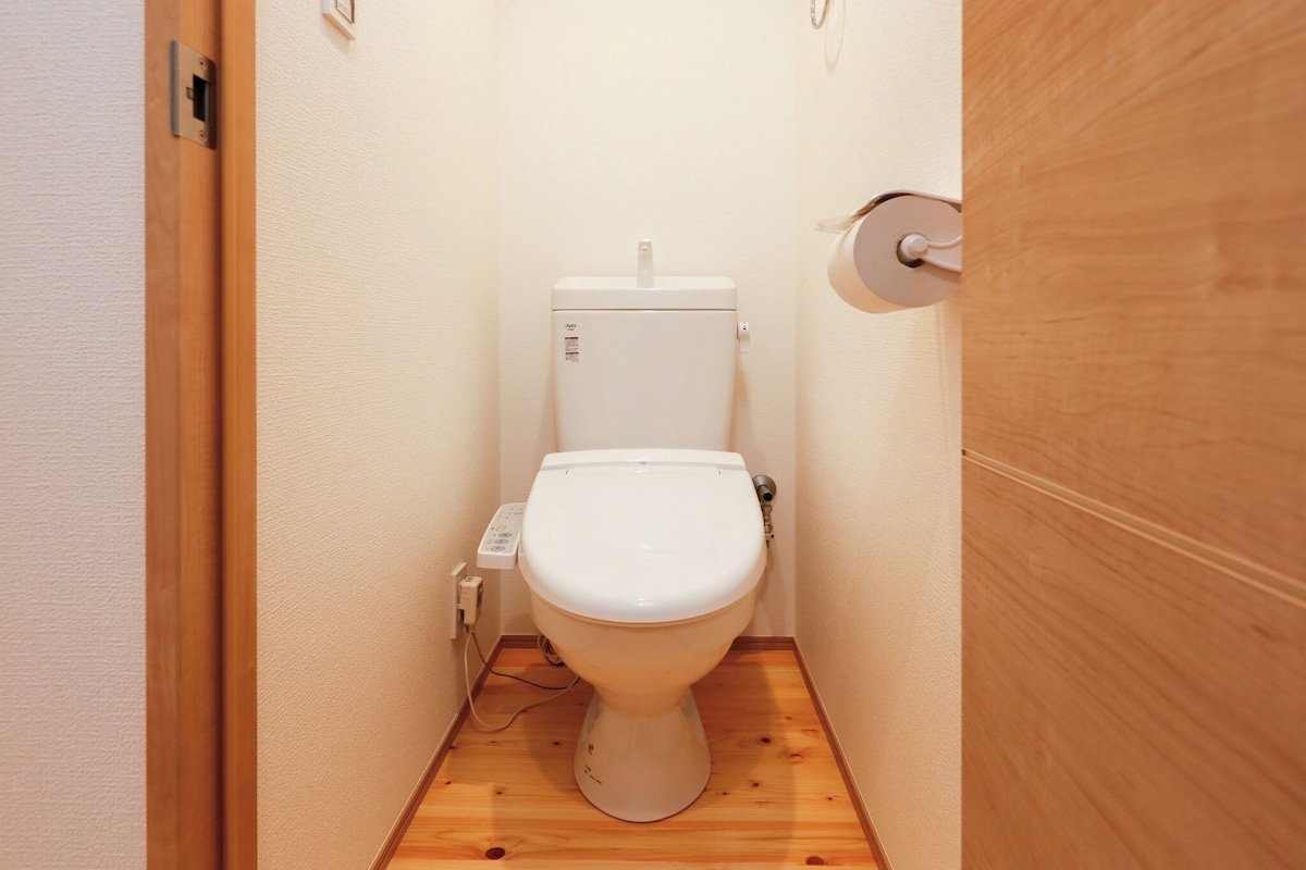 Une petite salle de bain aux dimensions réduites, avec des toilettes blanches, un plancher en bois et une porte en bois.