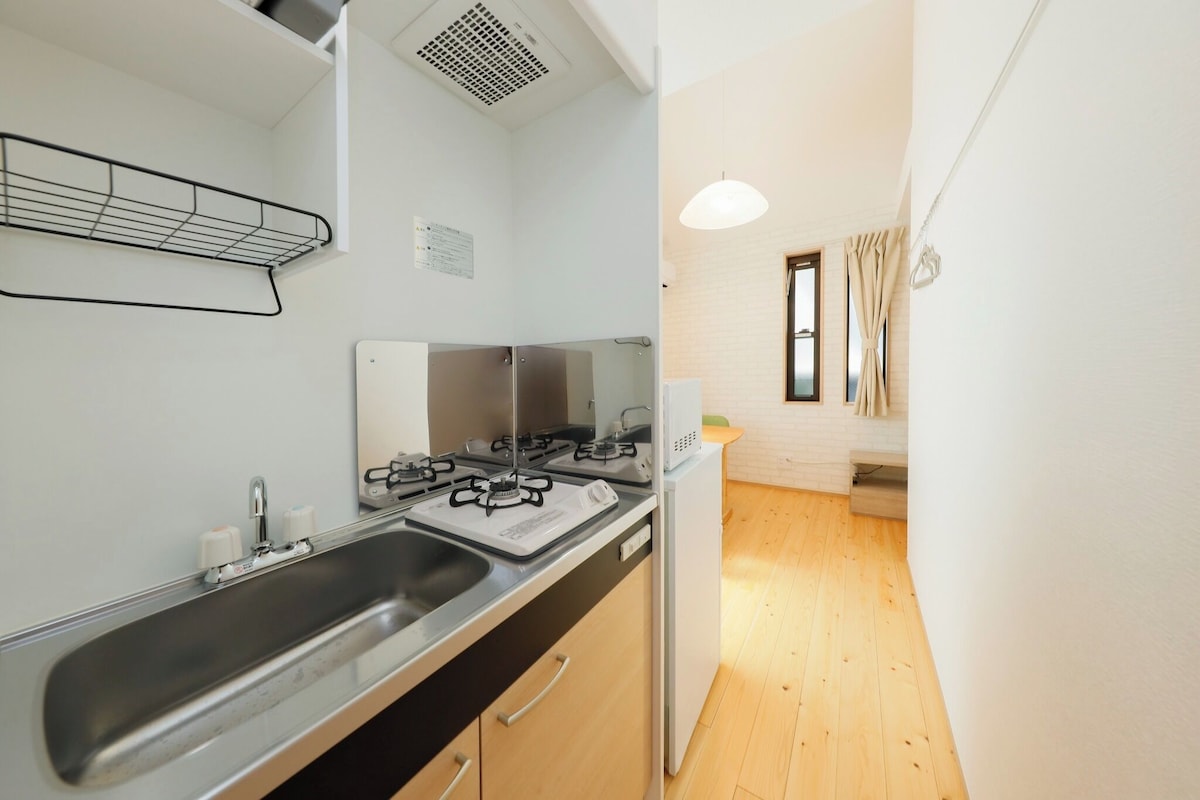 Une petite cuisine équipée d’un évier, d’une cuisinière et d’une petite fenêtre avec des rideaux.
