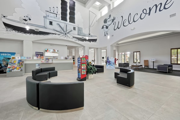 Un hall d’entrée spacieux, agrémenté d’une pancarte « Bienvenue », de sièges noirs, d’une grande fresque représentant un navire et d’un présentoir « Pandora ».