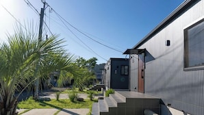 A modern house with a grey exterior, a front porch, and a small garden with palm trees. - LOCALINO STAY AOSHIMA (Miyazaki)